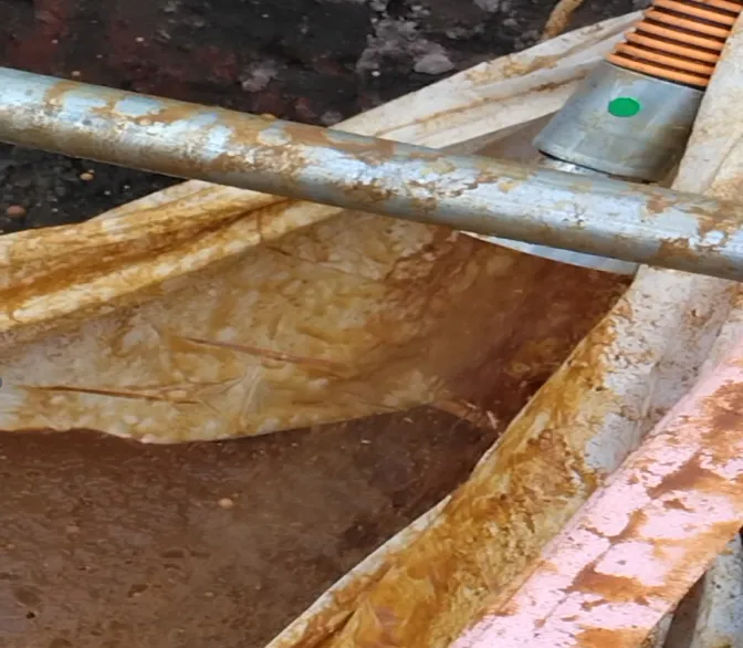 洗浄で回収された堆積物と濁水が現場の容器にたまっている写真