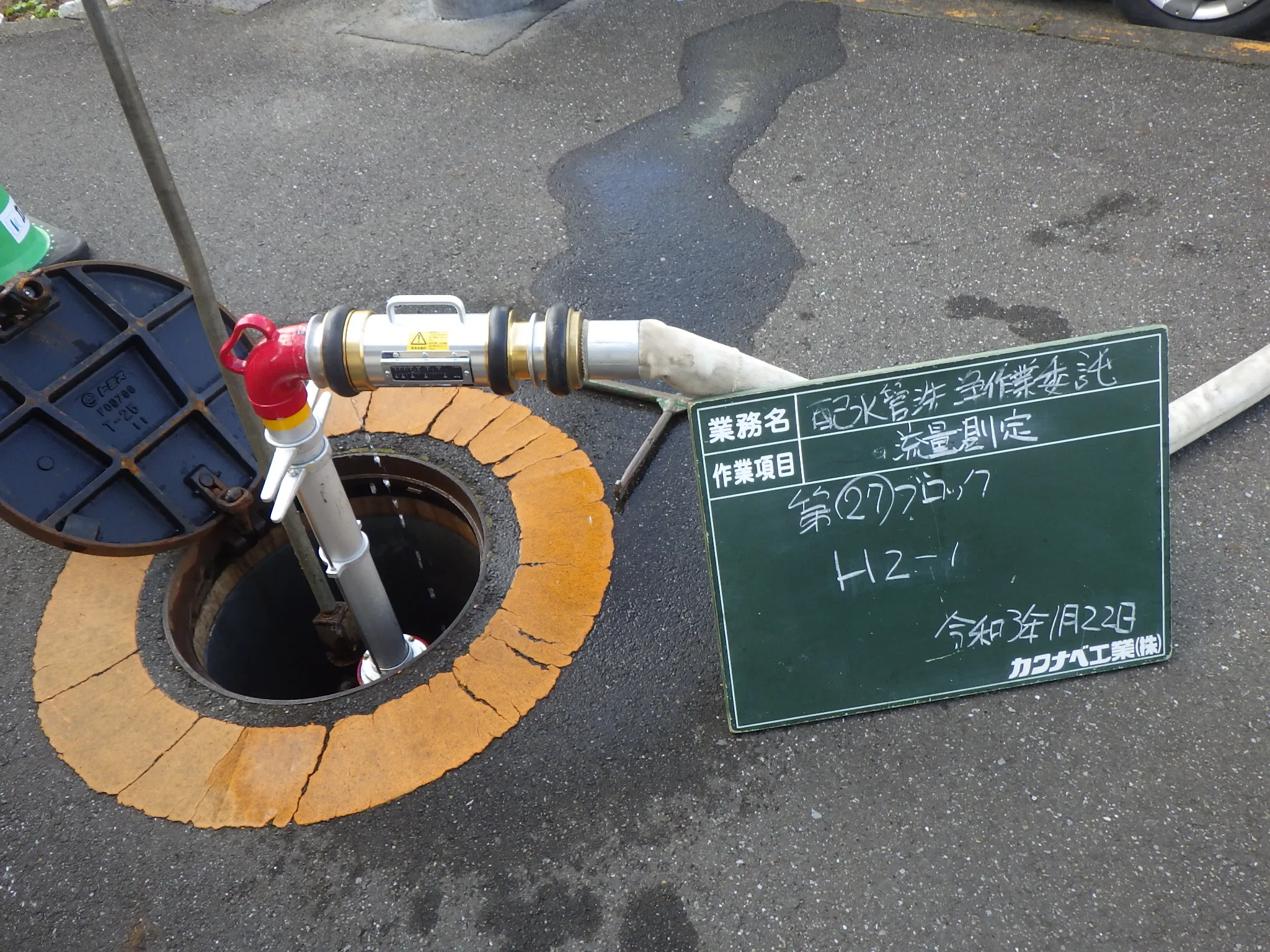 道路上の弁室に放水用の器具を取り付けている現場写真
