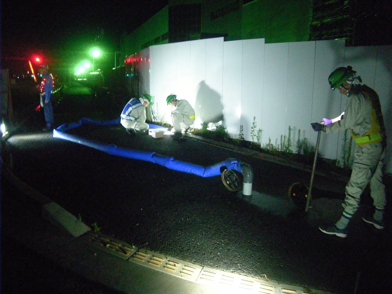 夜間、照明を立てて放水洗浄を行っている現場写真