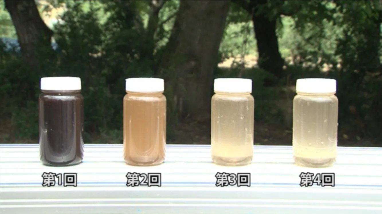 洗管1回目から4回目まで、採水サンプルの瓶4本を並べた写真。回を追うごとに濁りが薄くなっている